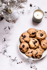 Homemade whisky and chocolate rye cookies,  silver artificial Christmas tree, tinsel and perfumed candle on grey background. Christmas cookies. Selective focus
