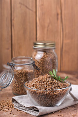 Cooked buckwheat in a glass, transparent bowl, parsley leaf, linen napkin, jars for storing cereals