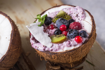 Tasty appetizing smoothie acai bowl made from blackberries and wild berries. Served in coconut bowl. Healthy life clean eating concept. Frozen dessert nice cream.
