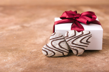 Two gingerbread hearts, in white glaze and chocolate lines, light gift box with burgundy satin bow