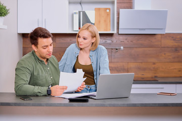 spouses sitting with laptop and documents, analyzing paperwork and house utility bills, financial issues, thoughtful couple consider papers managing finances and expenses, checking mail at home