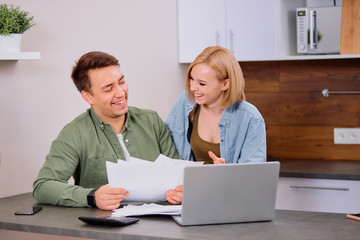 husband discussing contract details of financial issues with smiling happy wife. Married couple sit with paper document, making decision about house purchase, mortgage or financial investment.