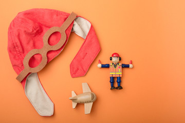 children's background, pilot's hat, toy wooden plane and man, orange background
