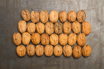 Nueces entera y con cáscara sobre mesa de madera gris rústica. Vista superior