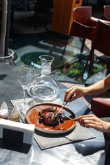 The girl in the restaurant eats an exquisite dish, beef medallion in blueberry sauce.