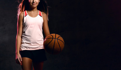 Beautiful caucasian teen woman in sportswear playing basketball . Sport concept isolated on black...