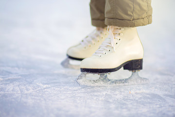 A child in figure skates stands on the ice, closeup skates.