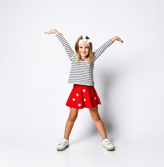 Happy child little girl in a red skirt and a striped T-shirt, with a perky hairband - has fun on a light background