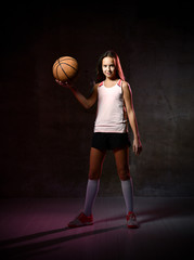 Naklejka premium Beautiful caucasian teen woman in sportswear playing basketball . Sport concept isolated on black background.