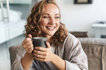 Cheerful young blonde haired woman drinking tea