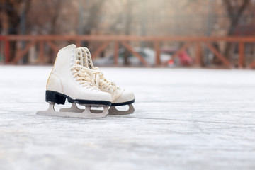 A pair of White Figure Skates are standing on an open ice rink. Winter sport