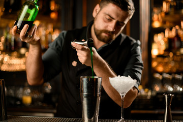 Bartender flows good alcohol from jigger to shaker
