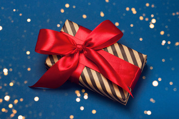 Luxuriously wrapped gift with lush ribbon. Trendy red and blue colors. Merry Christmas, St. Valentine's Day, Happy Birthday and other holidays concept.