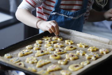 Kind mit Schürze dekoriert Weihnachtsplätzchen auf Backblech