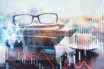 Financial graph hologram with glasses on the table background. Concept of business. Double exposure.