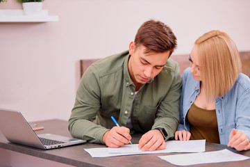 married caucasian couple make notes, going to buy new house or take mortgage, using laptop, planning finance at home