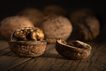 Peeled healthy walnut on dark vintage table. Dark moody food photography.
