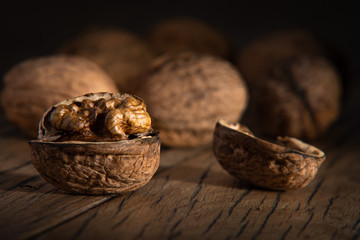 Peeled healthy walnut on dark vintage table. Nut is out of focus. Dark moody food photography.