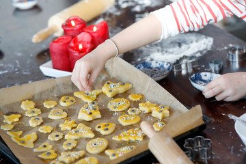 Kinder Hände backen, dekorieren bunte Weihnachtsplätzchen auf Backblech mit Zutaten, Zuckerstreusel, Nüssen.