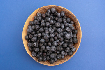 Bowl of blueberries in wooden bowl over blue background isolated. Fresh berry. Top view.