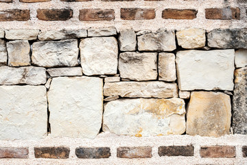 stone wall of large elements in cretinine and bricks on top and bottom