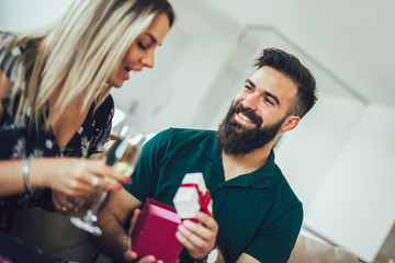 Young man giving a surprise gift to woman in the living room at home
