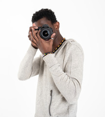 A black skin male photographer in a gray sweater and black pants is making photos with his black camera