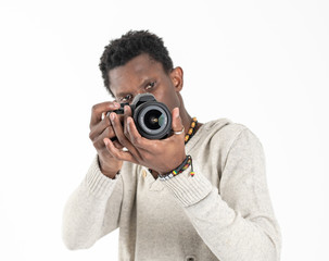 A black skin male photographer in a gray sweater and black pants is making photos with his black camera