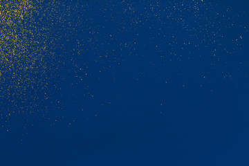 Gold glitter texture on a blue background. Design element. Golden explosion of confetti.
