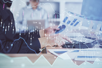 Double exposure of graph with man typing on computer in office on background. Concept of hard work. Closeup.