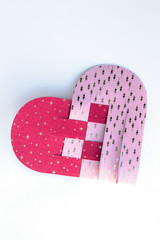 A half braided Christmas heart with golden stars and flowers on white background. DIY idea for Christmas. Illustration for instruction. Paper in pink rose and red in Scandinavian style.