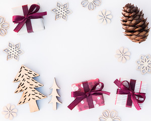 Still life with Christmas theme. Two small presents, a fir cone, wooden ornaments shaped as pine trees and snow flakes. Room in the middle for text or an item. Minimalistic style.