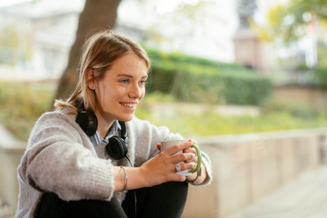 Young woman drinking coffee. Beautiful woman sitting on window and drinking hot drink.