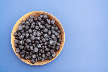 Bowl of blueberries in wooden bowl over blue background isolated. Fresh berry. Copy space.