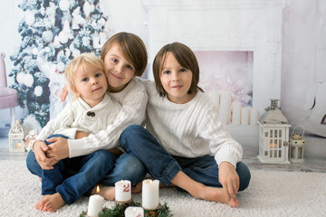 Obraz premium Three children, boy brothers, reading book at home at night on Christmas evening