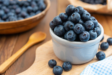 Ripe blueberries in the bowl on the wooden table. Fresh berries for breakfast.