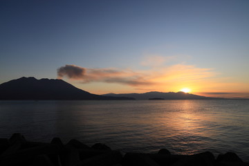 噴煙を上げる火山島と日の出