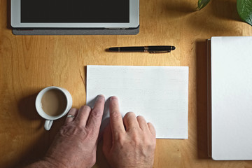 Blind person touching reading a braille text on a desk in a workplace. Accessibility in the classrom concept.