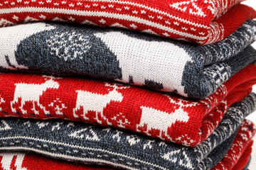 Stack of folded knitted Christmas turtleneck sweaters closeup