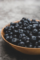 Bowl of blueberries in wooden bowl over grey background isolated. Fresh berry. Copy space.