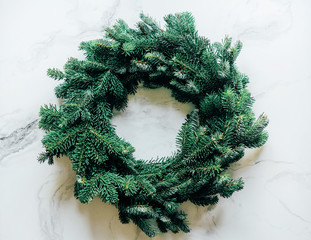 One natural spruce Christmas wreath, fluffy and fragrant, in the center of the image on a marble background. Stylish conceptual minimalism.