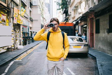 Tourist with photo camera standing on street side