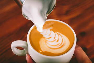 Cup of coffee cappuccino for lefties  with cream wooden background