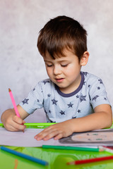 Little boy drawing with color pencils. Boy, drawing a picture for fathers day. Small boy draws at the table.