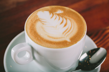 Cup of coffee cappuccino for lefties  with cream wooden background