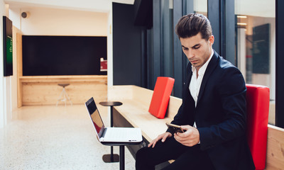 Busy businessman surfing smartphone in office