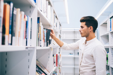 Educated guy finding book in library
