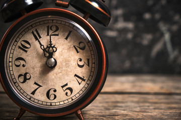 Old retro alarm clock on wooden table. Time is ticking and the hands.