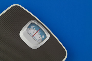Scale on blue background with space for text. Loose weight and overweight concept.