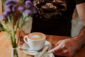 Midsection of man drinking cappuccino in cafe in Berlin